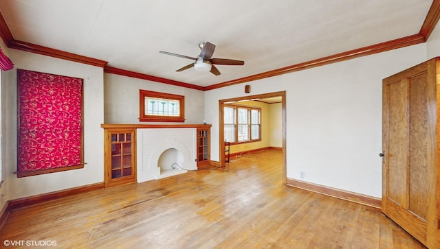 unfurnished living room featuring crown molding, ceiling fan, wood-type flooring, and a brick fireplace