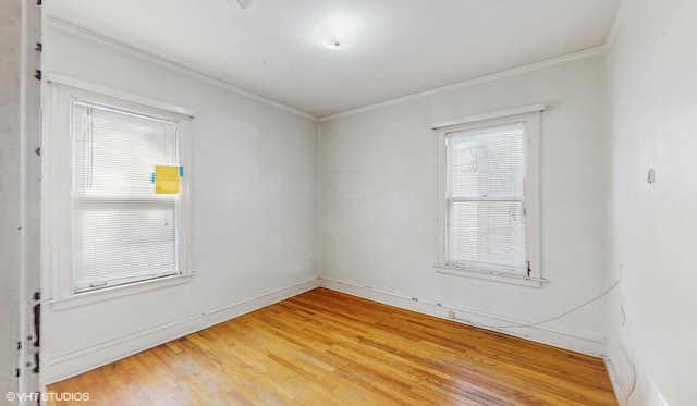 spare room with wood-type flooring, a wealth of natural light, and crown molding