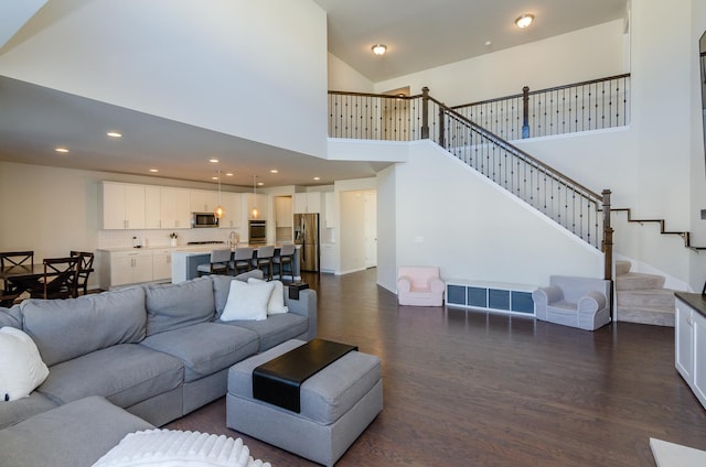 living room with stairs, recessed lighting, a high ceiling, baseboards, and dark wood-style flooring