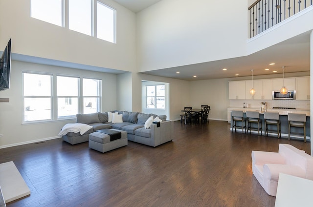 living room with baseboards, plenty of natural light, and dark wood-type flooring