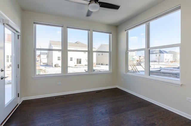 unfurnished room featuring dark wood finished floors, visible vents, ceiling fan, and baseboards