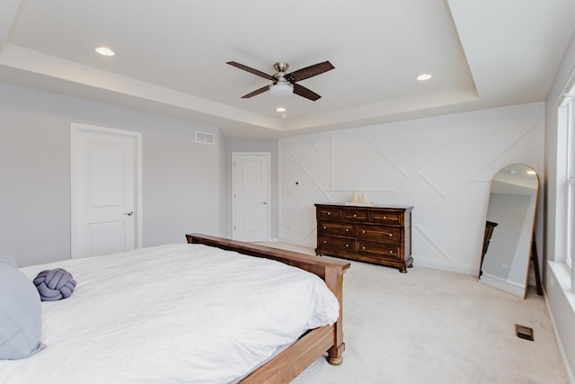 bedroom featuring visible vents, a tray ceiling, recessed lighting, ceiling fan, and light carpet