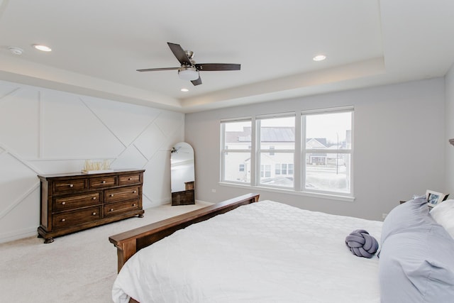 carpeted bedroom with a tray ceiling, recessed lighting, baseboards, and ceiling fan