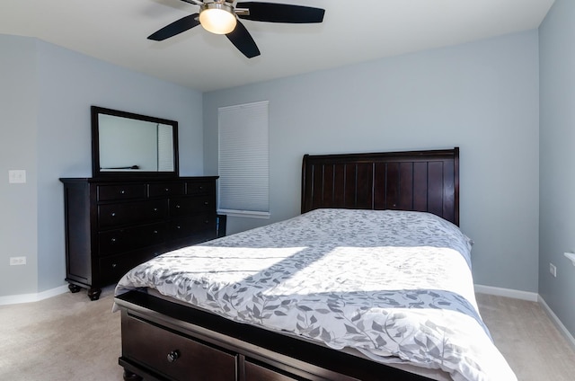 bedroom featuring light colored carpet, a ceiling fan, and baseboards