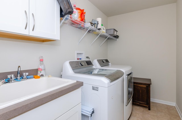 washroom featuring a sink, baseboards, cabinet space, and washing machine and dryer