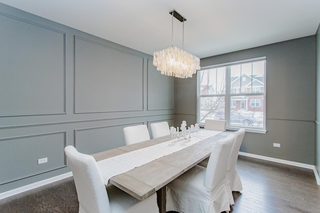 dining area with an inviting chandelier, a decorative wall, wood finished floors, and baseboards