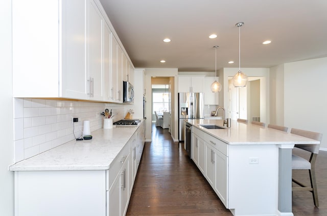 kitchen featuring a breakfast bar, white cabinets, stainless steel appliances, and a sink