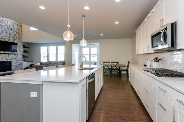 kitchen with backsplash, dark wood finished floors, open floor plan, appliances with stainless steel finishes, and a sink