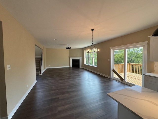 unfurnished living room with dark hardwood / wood-style floors and a notable chandelier