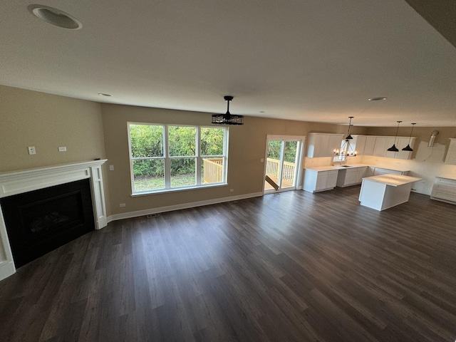 unfurnished living room featuring dark hardwood / wood-style floors and an inviting chandelier