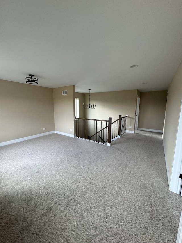 carpeted empty room featuring an inviting chandelier