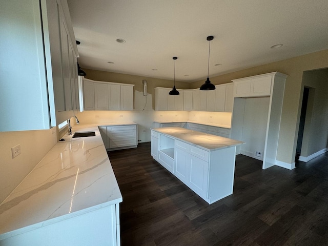 kitchen featuring dark hardwood / wood-style flooring, sink, pendant lighting, white cabinets, and a kitchen island