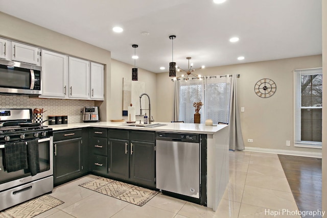 kitchen featuring stainless steel appliances, sink, decorative light fixtures, a notable chandelier, and white cabinets