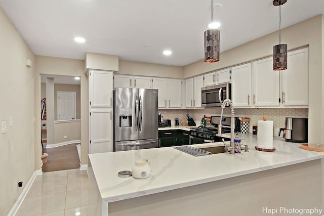 kitchen featuring white cabinets, light tile patterned floors, stainless steel appliances, and hanging light fixtures