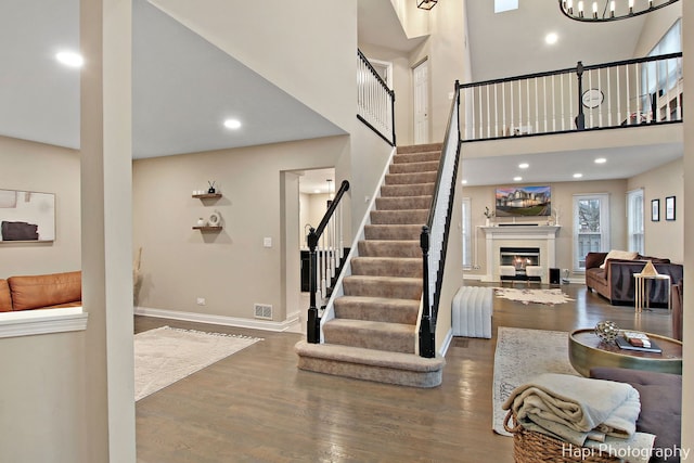 stairs with wood-type flooring and a towering ceiling