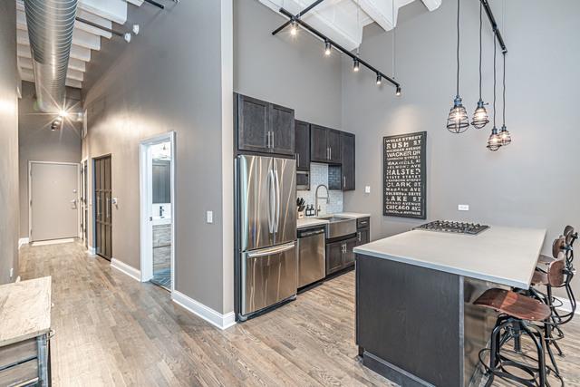 kitchen featuring appliances with stainless steel finishes, light hardwood / wood-style flooring, pendant lighting, and a high ceiling