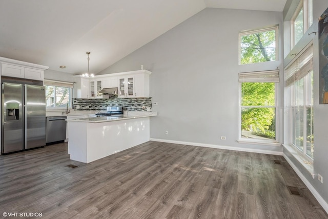 kitchen featuring white cabinetry, hanging light fixtures, backsplash, kitchen peninsula, and appliances with stainless steel finishes