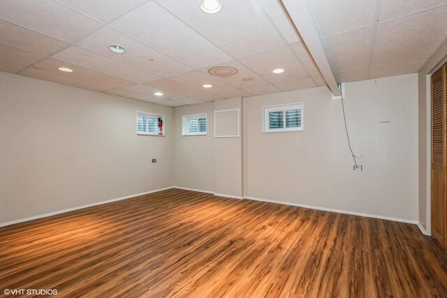 basement with dark hardwood / wood-style flooring and a paneled ceiling