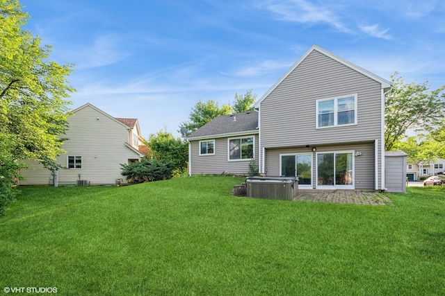 back of property with a yard and a hot tub