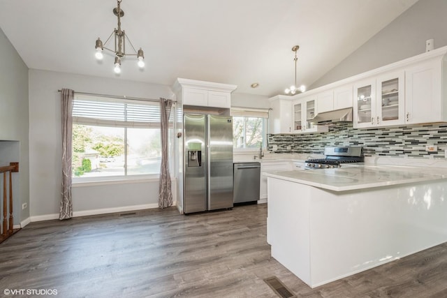 kitchen with ventilation hood, stainless steel appliances, white cabinetry, hanging light fixtures, and lofted ceiling