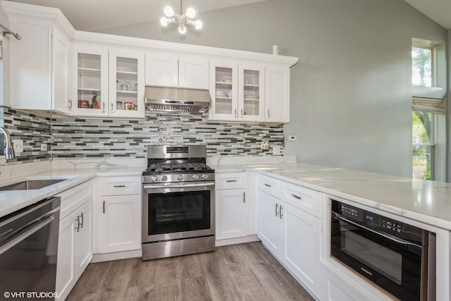 kitchen with white cabinets, appliances with stainless steel finishes, vaulted ceiling, and exhaust hood