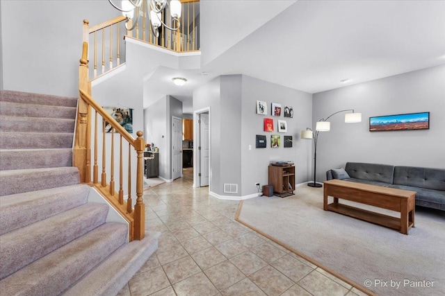 living room with a towering ceiling, tile patterned floors, and a chandelier