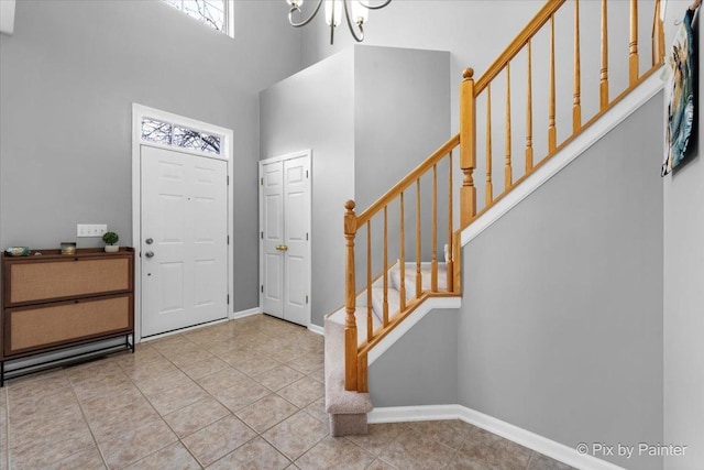 tiled foyer entrance with an inviting chandelier and a towering ceiling