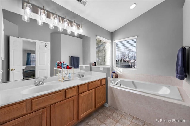 bathroom featuring vanity, tile patterned flooring, vaulted ceiling, and tiled tub