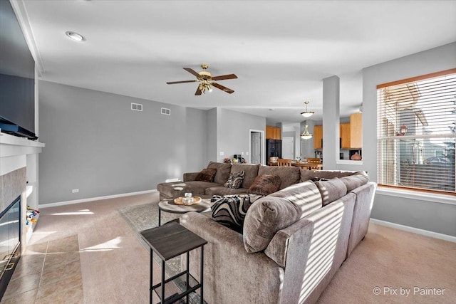 carpeted living room featuring a fireplace and ceiling fan