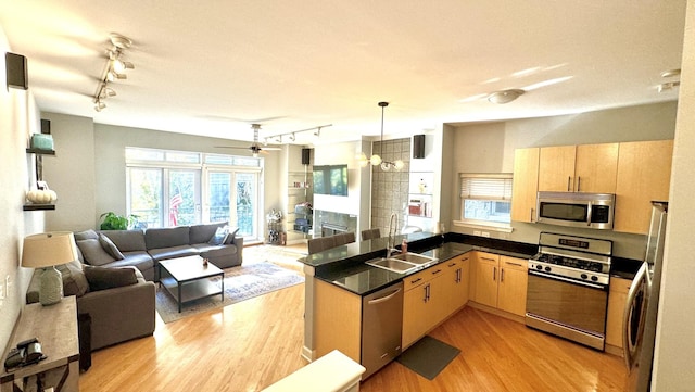 kitchen with hanging light fixtures, ceiling fan, light brown cabinetry, kitchen peninsula, and stainless steel appliances