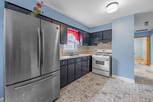 kitchen featuring tasteful backsplash, stainless steel fridge, white gas stove, and sink