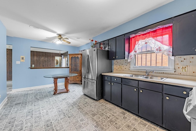 kitchen featuring backsplash, ceiling fan, sink, range, and stainless steel refrigerator