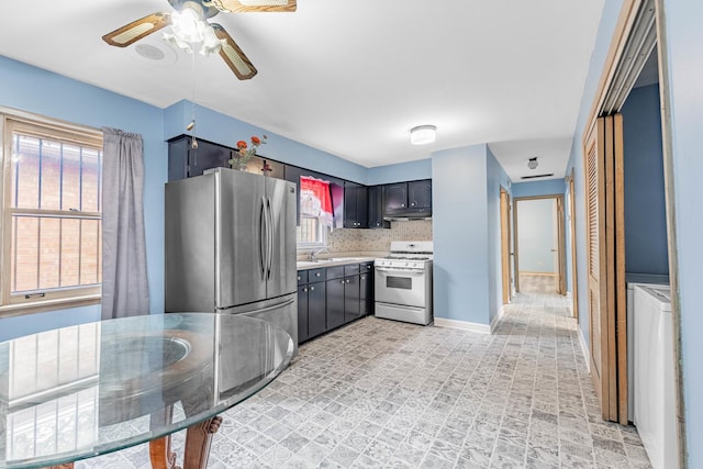 kitchen featuring backsplash, white range oven, sink, washer / dryer, and stainless steel refrigerator