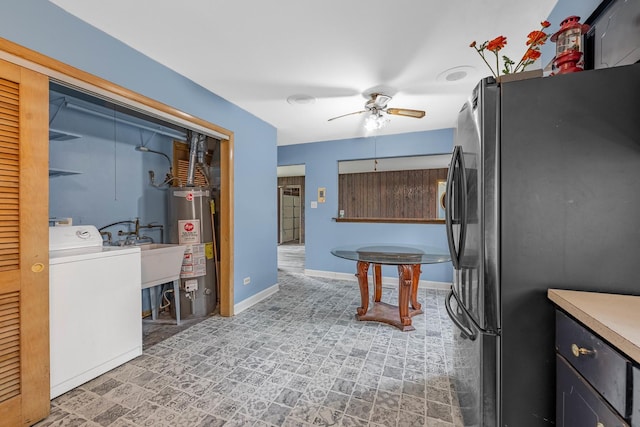 kitchen featuring ceiling fan, sink, gas water heater, stainless steel fridge, and washer / dryer