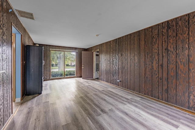 unfurnished living room featuring wooden walls and light hardwood / wood-style floors