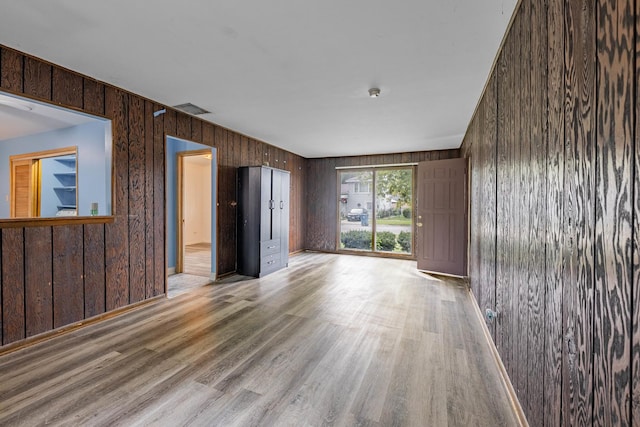 empty room featuring wood walls and light wood-type flooring