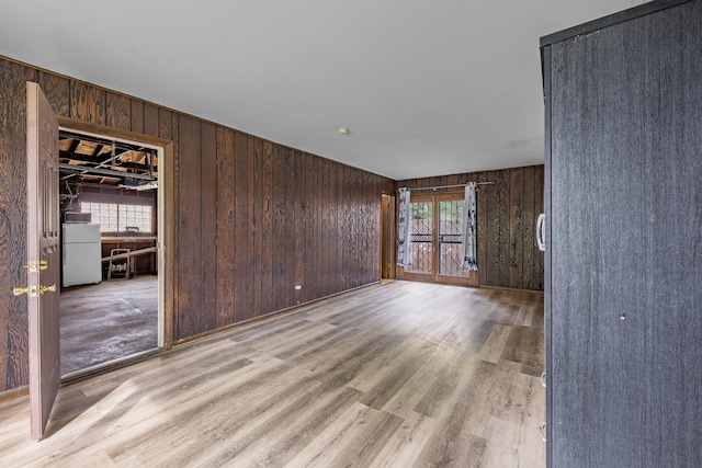 unfurnished living room with light wood-type flooring and wood walls