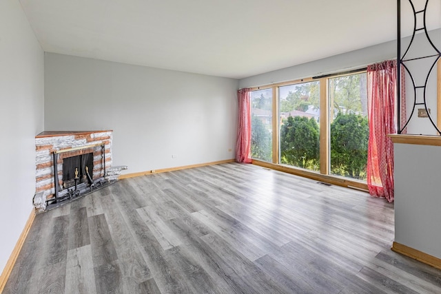 unfurnished living room featuring hardwood / wood-style floors and a brick fireplace