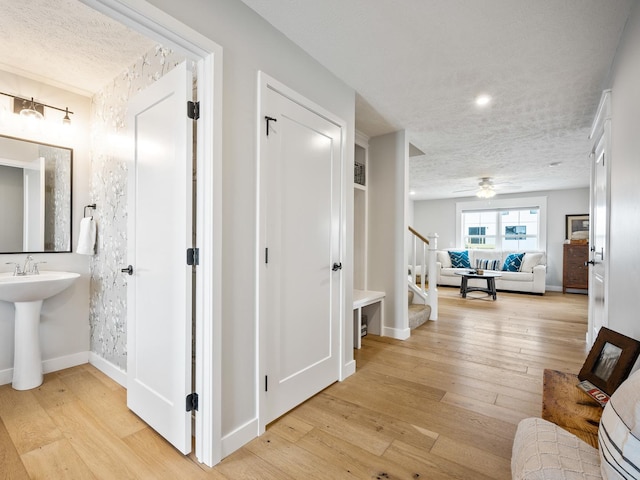 hall featuring light hardwood / wood-style flooring, a textured ceiling, and sink