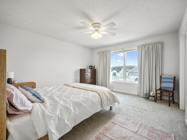 bedroom featuring a textured ceiling, light colored carpet, and ceiling fan