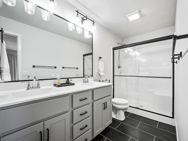 bathroom with vanity, a textured ceiling, toilet, and a shower with shower door