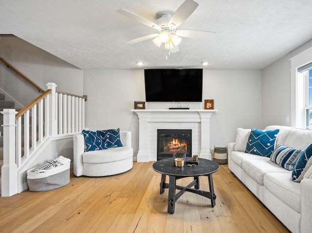 living room with ceiling fan, hardwood / wood-style floors, and a textured ceiling