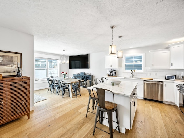 kitchen with stainless steel dishwasher, a center island, pendant lighting, and tasteful backsplash