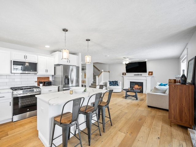 kitchen featuring appliances with stainless steel finishes, a breakfast bar, pendant lighting, a center island, and white cabinetry