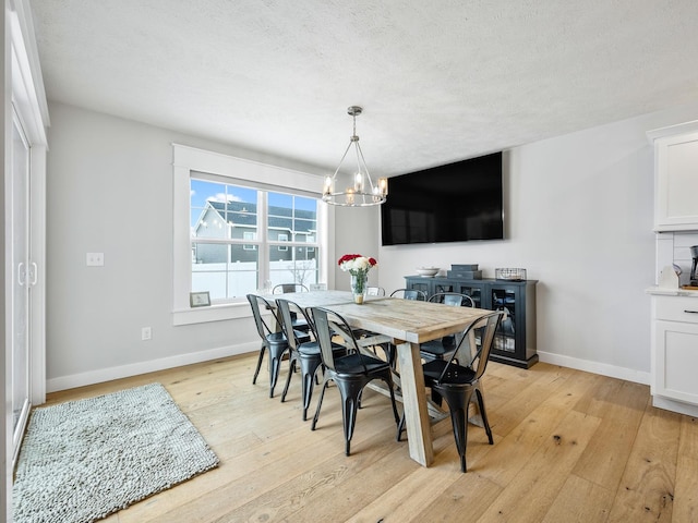 dining space featuring a chandelier, a textured ceiling, and light wood-type flooring