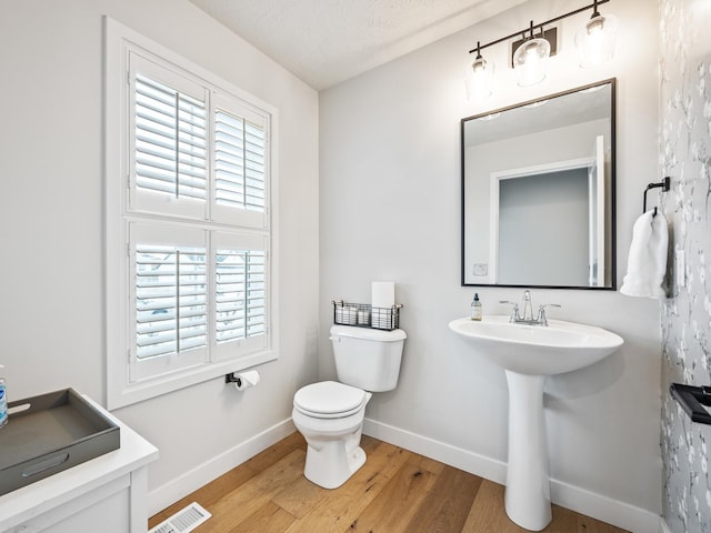 bathroom with sink, toilet, wood-type flooring, and a textured ceiling