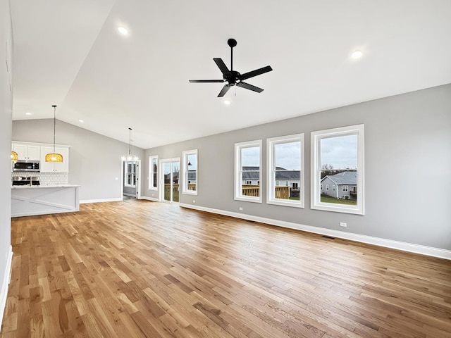 unfurnished living room featuring ceiling fan with notable chandelier, light wood-type flooring, and lofted ceiling