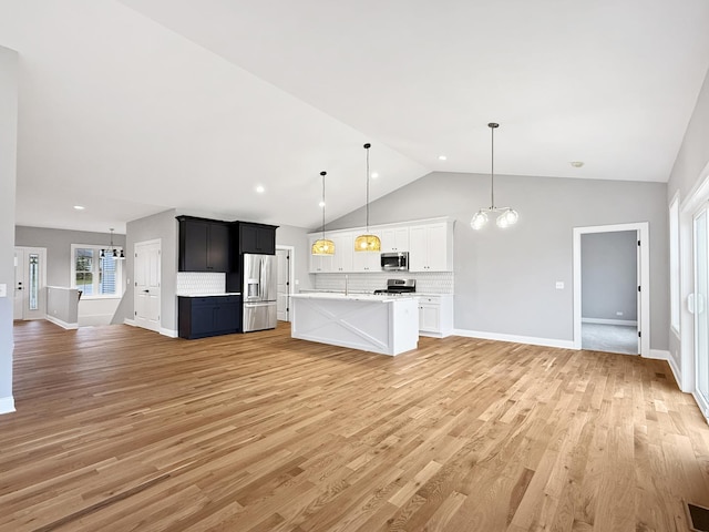 unfurnished living room featuring a notable chandelier, lofted ceiling, and light wood-type flooring