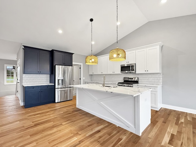 kitchen featuring a center island with sink, appliances with stainless steel finishes, tasteful backsplash, decorative light fixtures, and white cabinetry