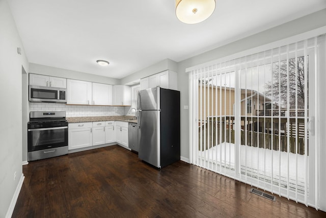 kitchen with white cabinets, dark hardwood / wood-style flooring, stainless steel appliances, and tasteful backsplash